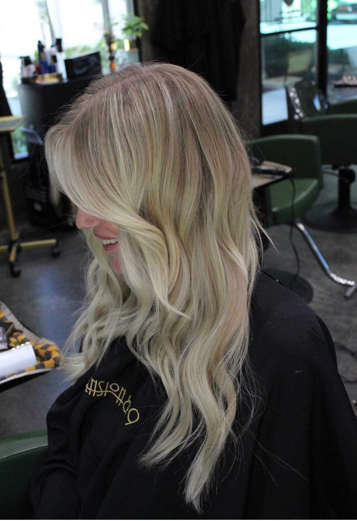 Long blonde wavy hair styled in a salon chair.