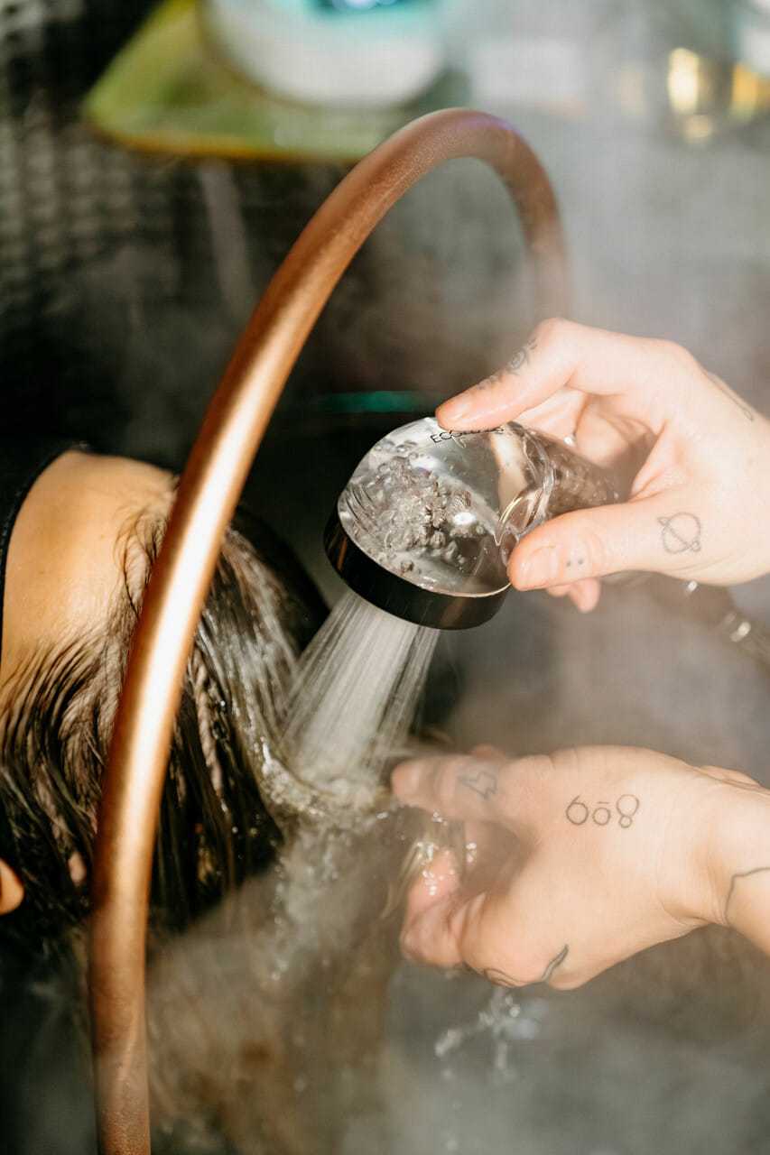 Steam hair treatment with water being rinsed in salon setting.
