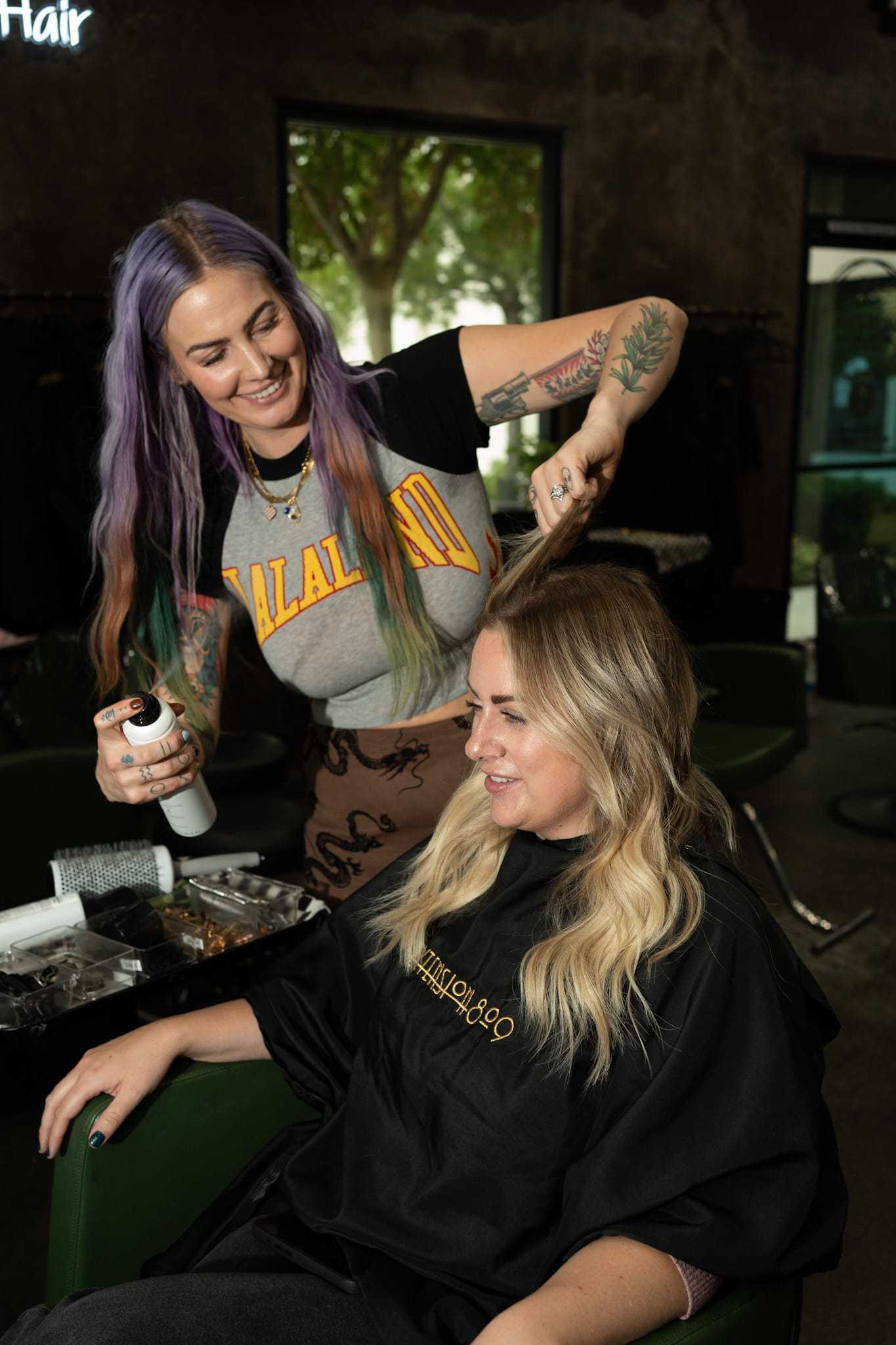 Hairdresser styling client's hair with a smile in a salon.